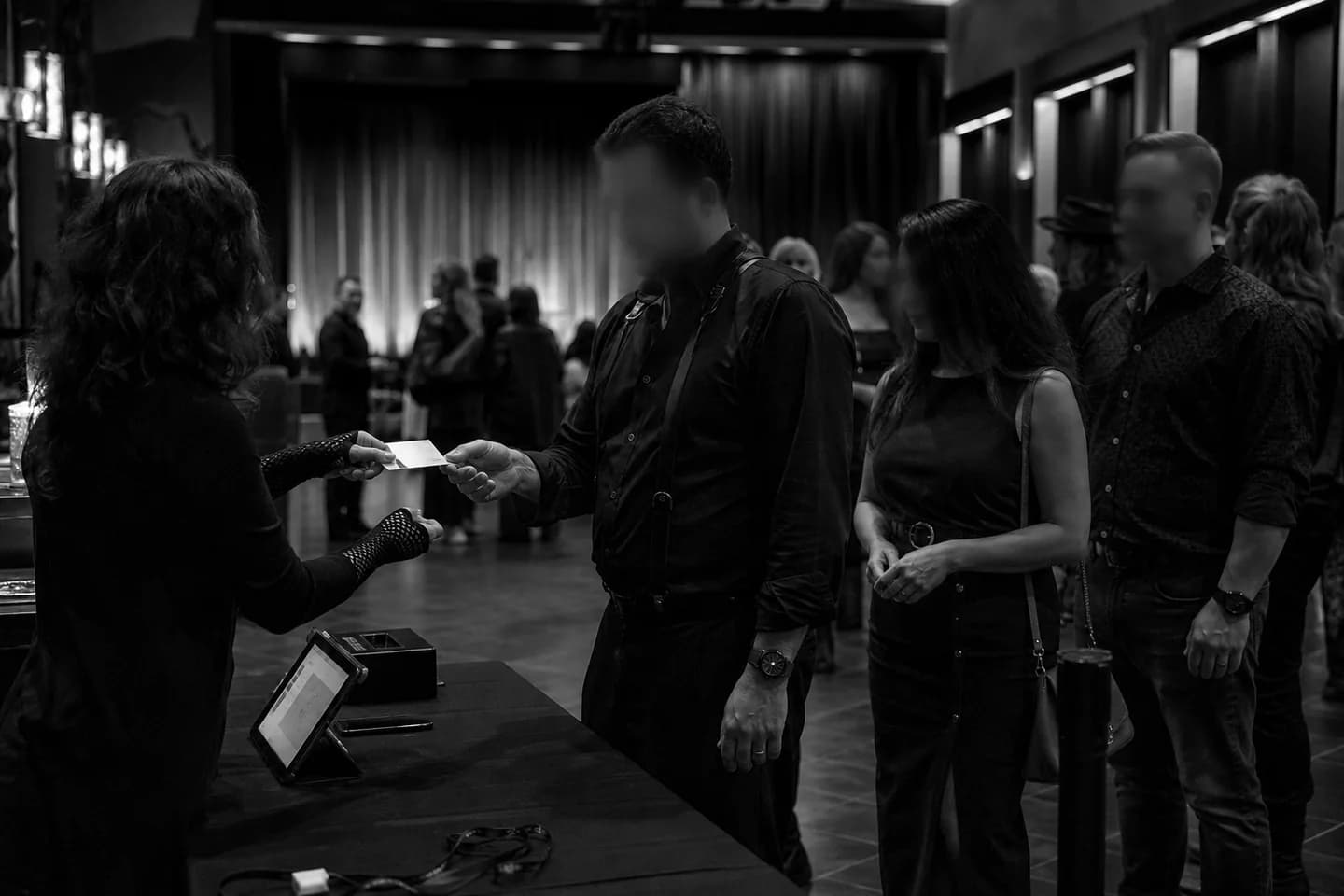 Adult guests checking into a monochrome evening event with tickets and wristbands.