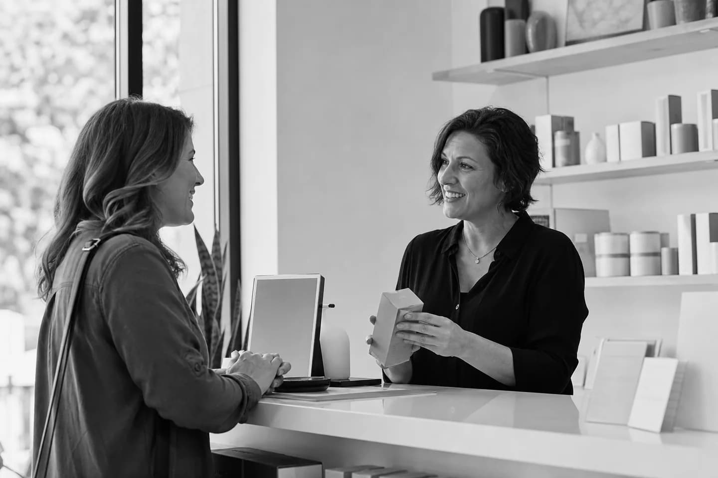An adult customer speaking with a friendly wellness boutique associate in black and white.